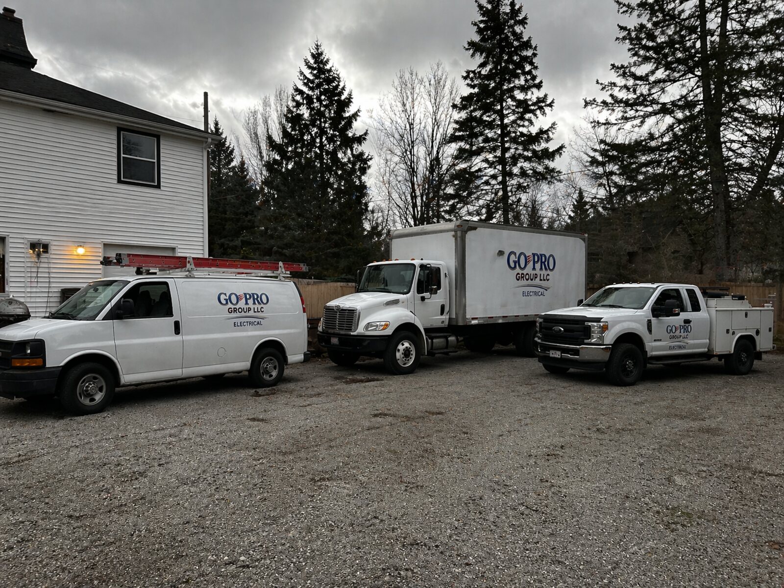 Three Go Pro Group LLC service vehicles — a cargo van, box truck, and utility pickup — staged and ready to roll